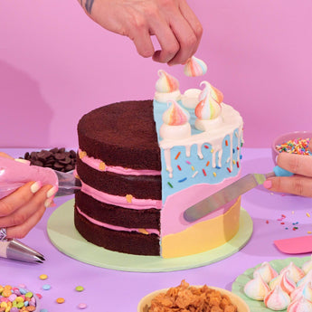 Design your own Cake being decorated with pastel icing, meringues, and sprinkles by Crumbs & Doilies experts